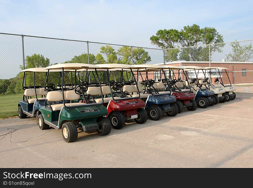 Golf carts lined up in a row ready for use.