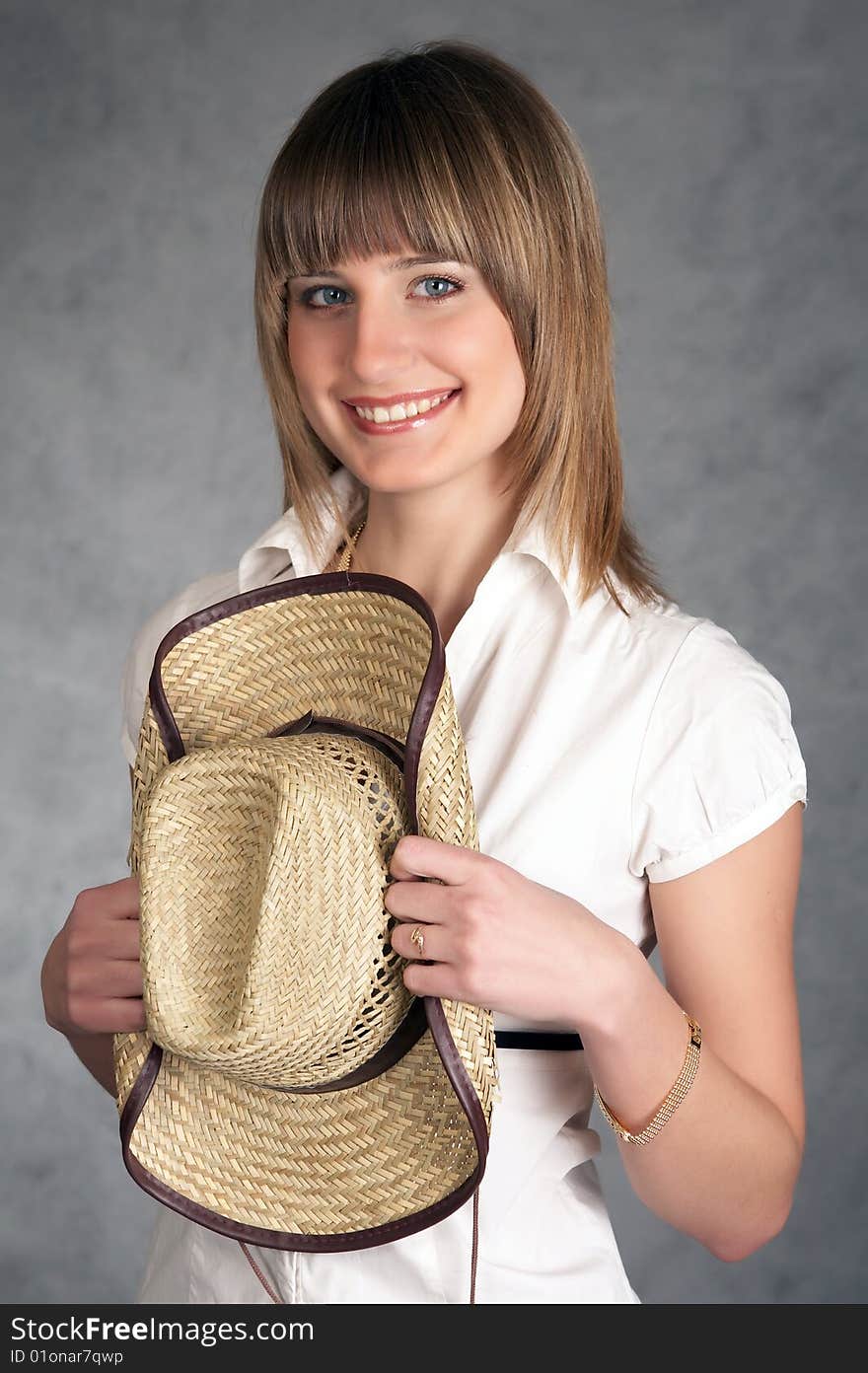 Cowgirl in a hat on a grey background possing in a studio. Cowgirl in a hat on a grey background possing in a studio