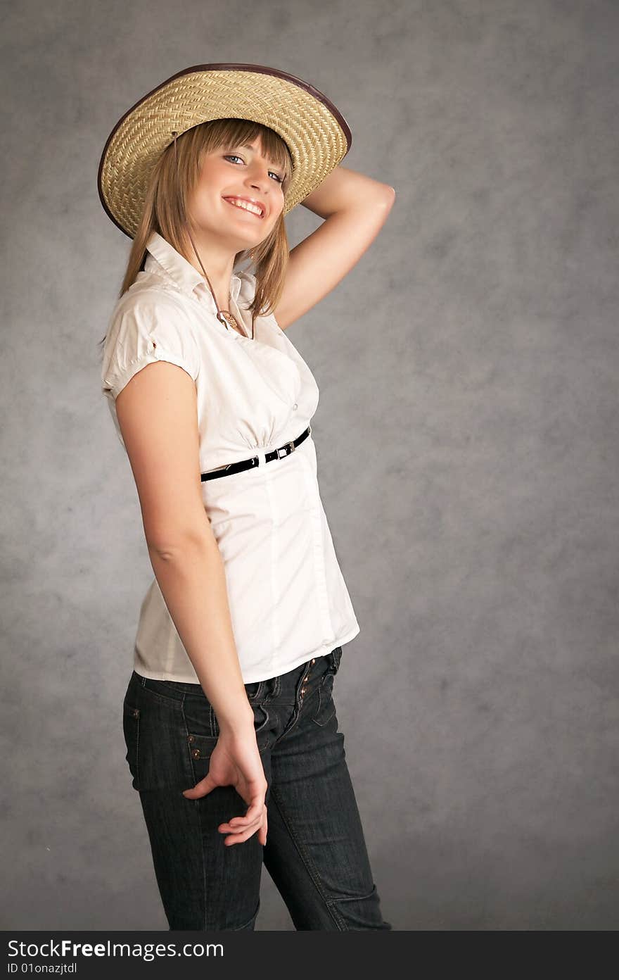 Cowgirl in a hat on a grey background possing in a studio