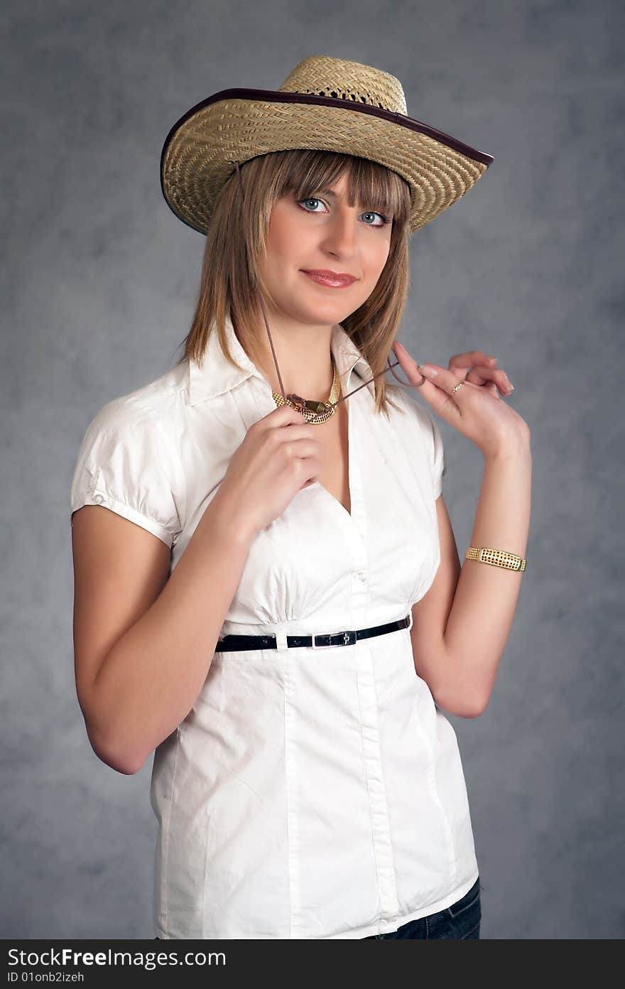 Cowgirl in a hat on a grey background possing in a studio