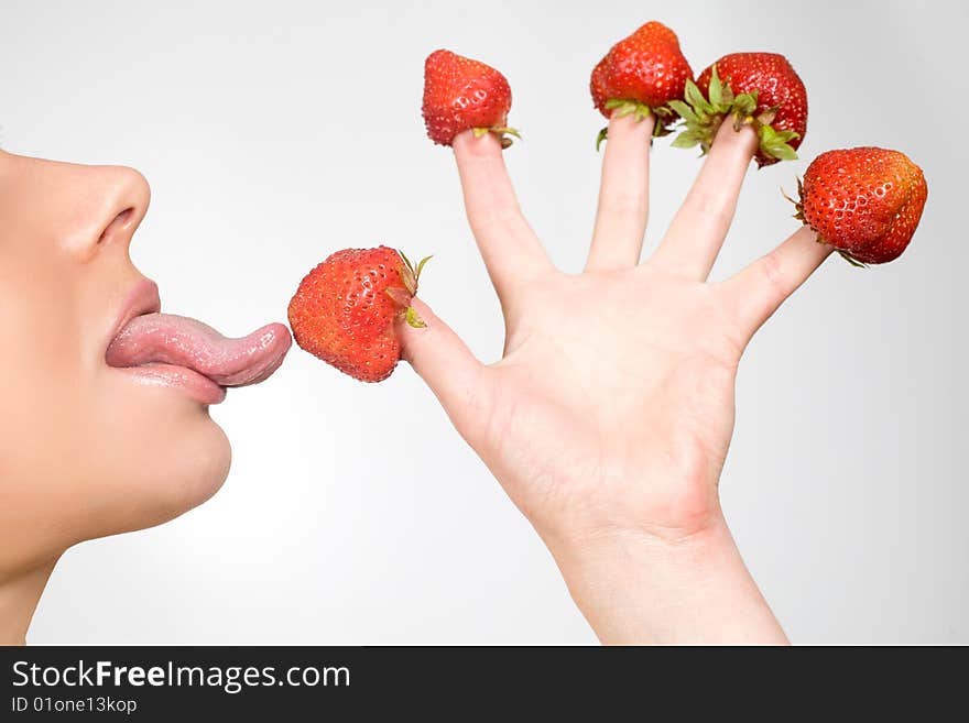 Sweet caucasian girl eating strawberries picked on fingertips