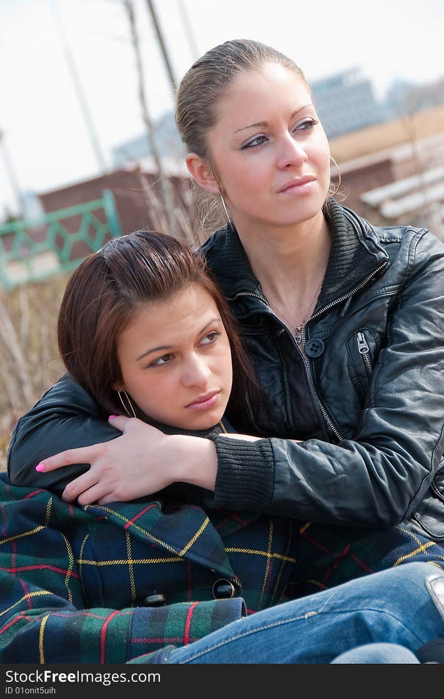 Two young girls relax on a bench in a park. Two young girls relax on a bench in a park