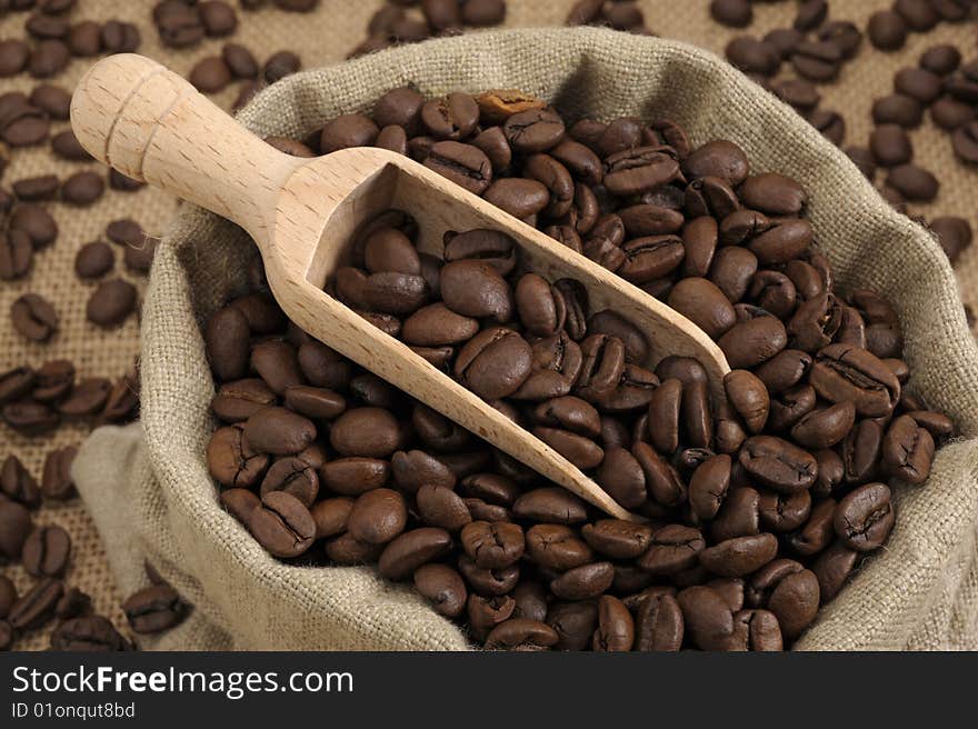 Coffee beans in an natural bag with a wooden scoop