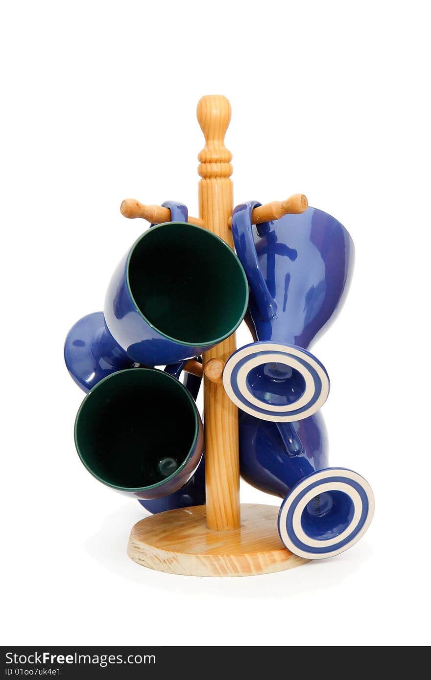 Four blue long-stemmed coffee cups on wooden rack isolated. Four blue long-stemmed coffee cups on wooden rack isolated