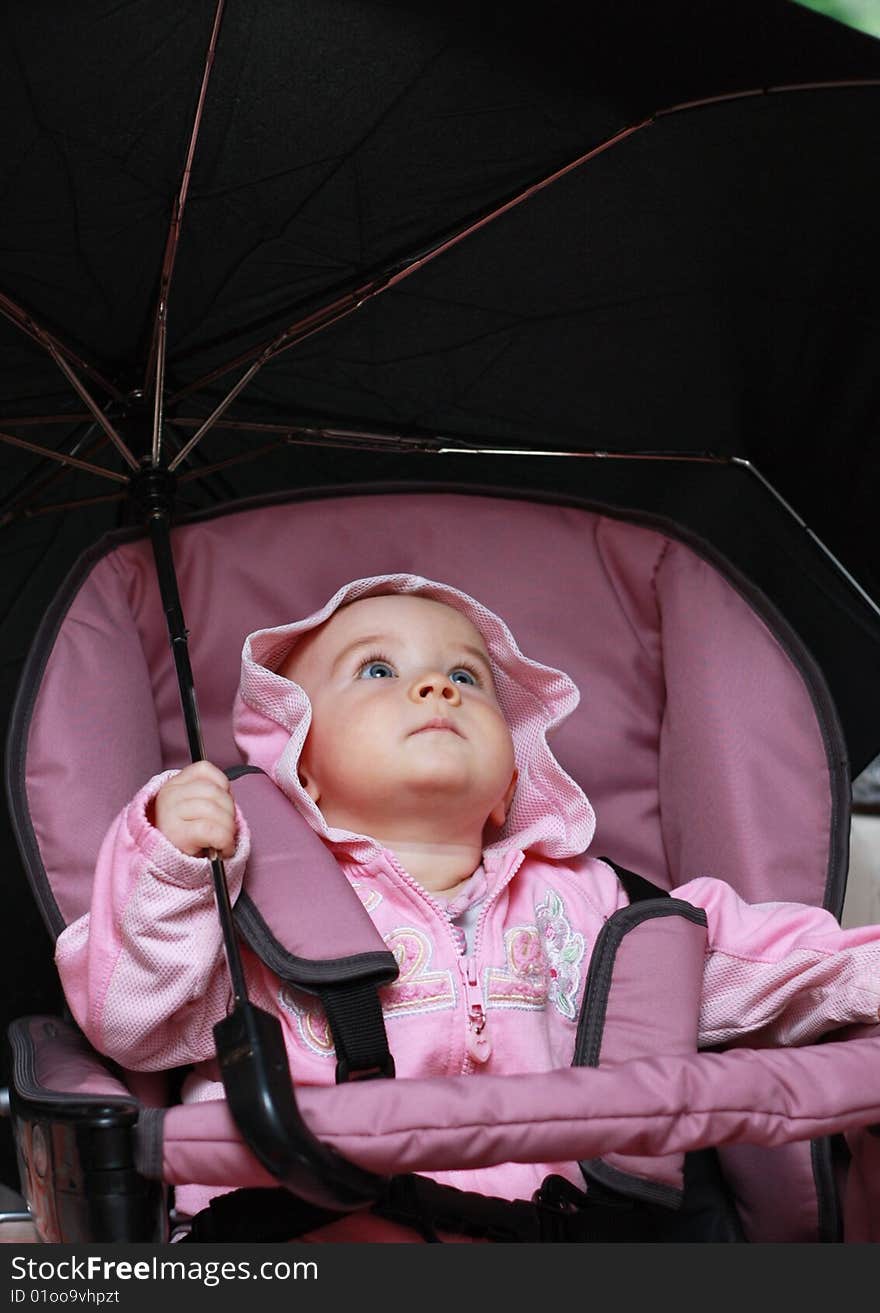 Baby sitting in a pram and holding a large umbrella. Baby sitting in a pram and holding a large umbrella