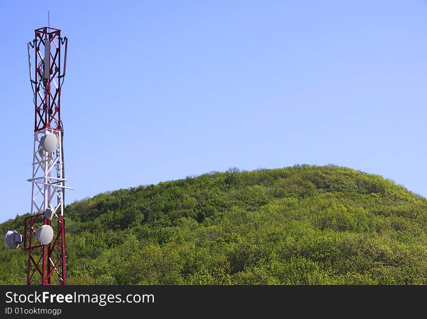 Telecommunication tower over blue sky and forest background