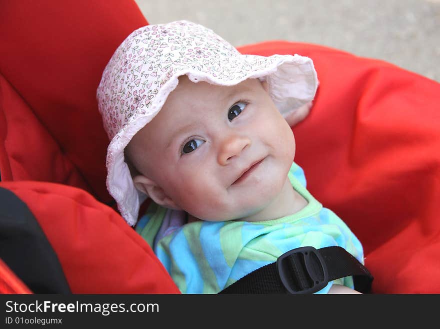 Happy baby girl with panama sitting in carriage. Happy baby girl with panama sitting in carriage