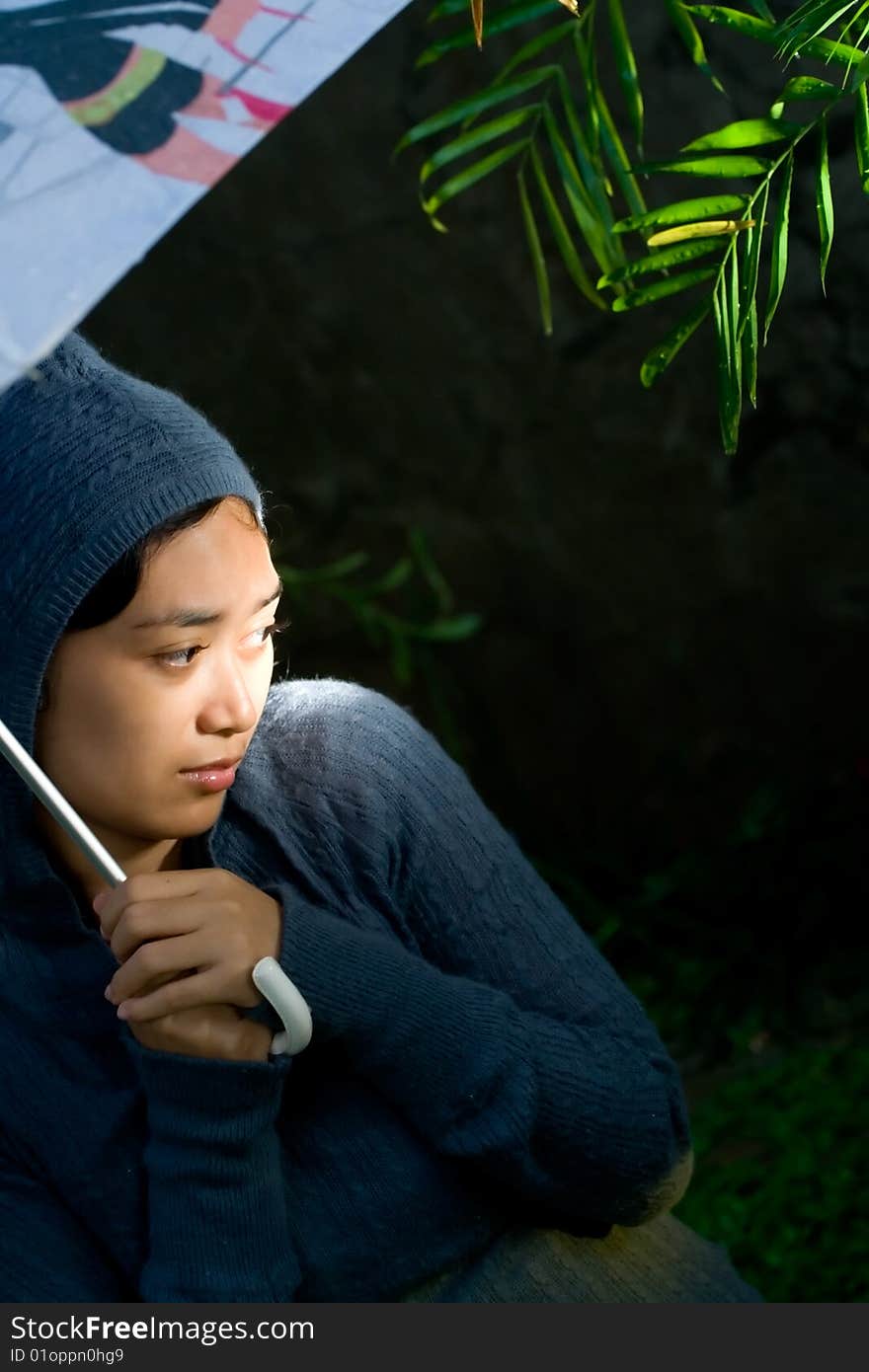 Portrait of asian woman on her sweater and holding an umbrella on a cold and rainy night. seems to worry of something and feeling insecure of her current circumstances. Portrait of asian woman on her sweater and holding an umbrella on a cold and rainy night. seems to worry of something and feeling insecure of her current circumstances.