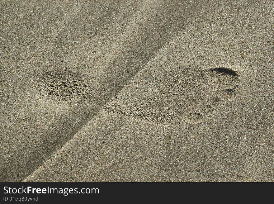 A footstep on the sand of a beach