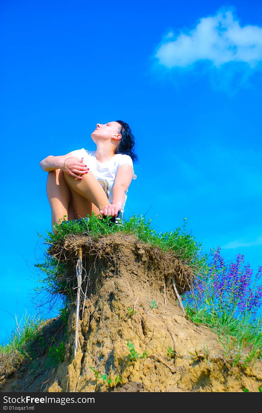 Girl sitting on a top of a hill. Girl sitting on a top of a hill