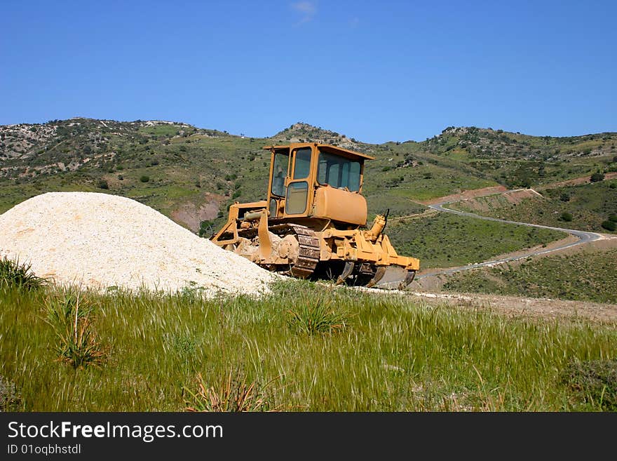 Tractor on a hill against the background of mountains and a road