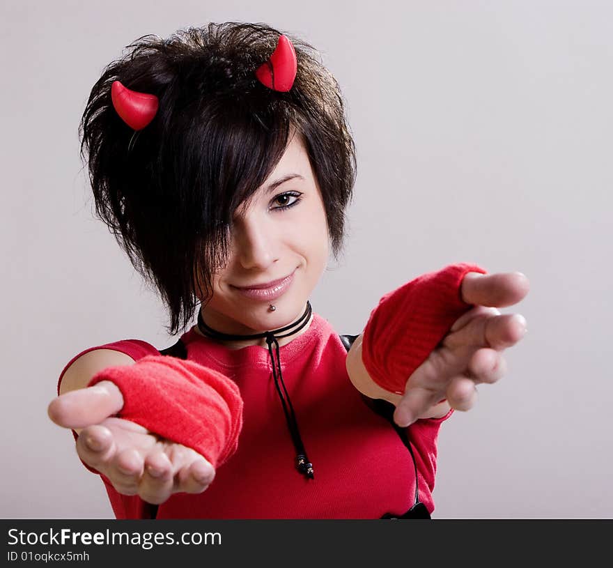 A young sexual girl in an image of a devil  in red and black with  horns on her head posing on a light background. A young sexual girl in an image of a devil  in red and black with  horns on her head posing on a light background