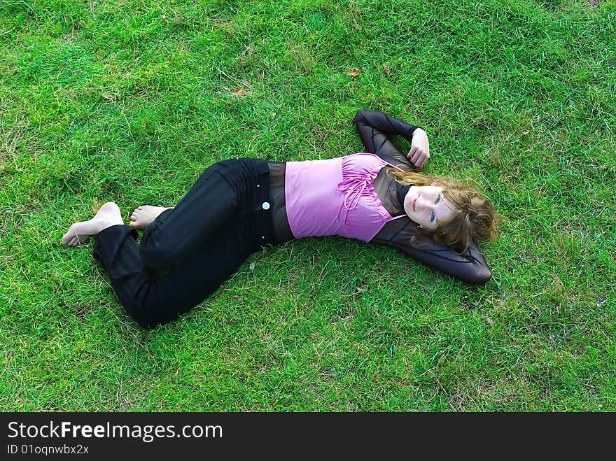 Young woman with red hairs lays in the grass. Young woman with red hairs lays in the grass