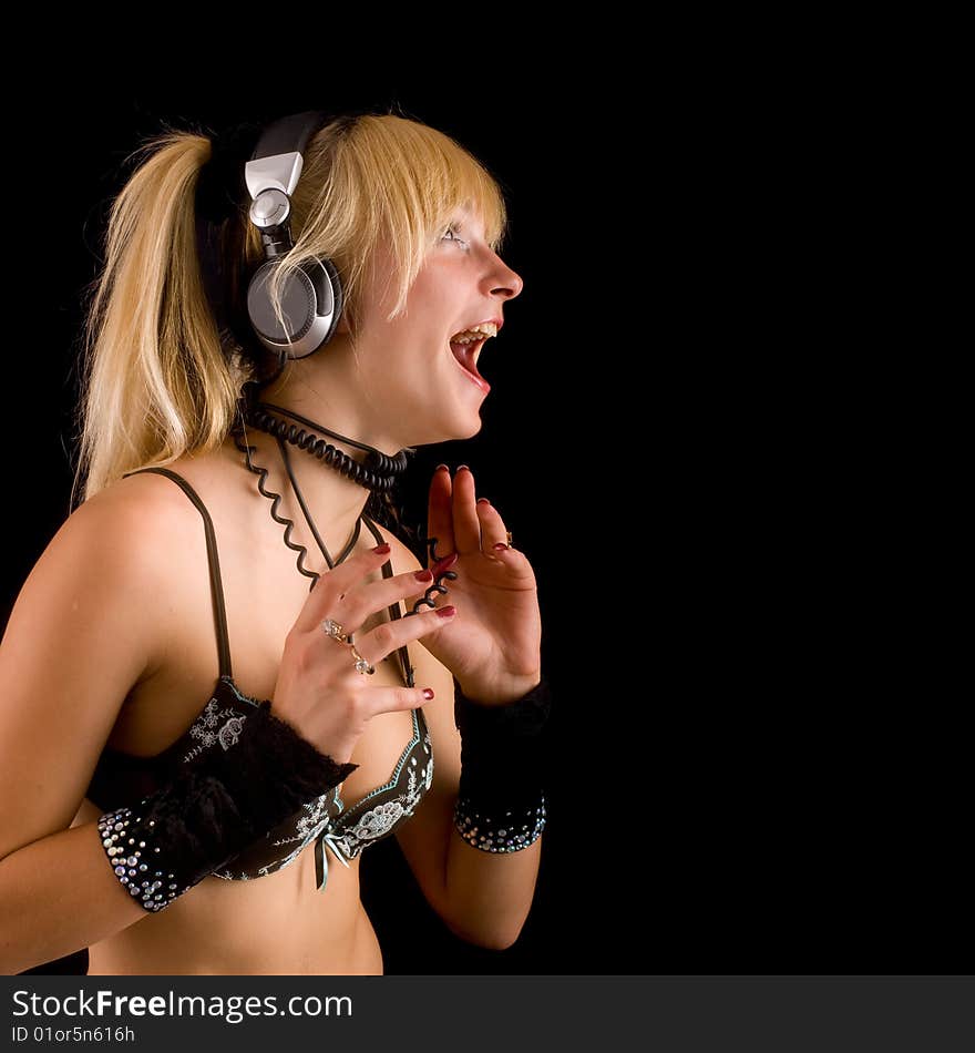 Young girl in their underwear listening to music in headphones on a black background. Young girl in their underwear listening to music in headphones on a black background