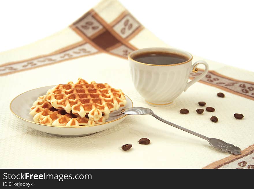 Wafers on a saucer, a porcelain cup from coffee, grains, a teaspoon on a napkin. Wafers on a saucer, a porcelain cup from coffee, grains, a teaspoon on a napkin