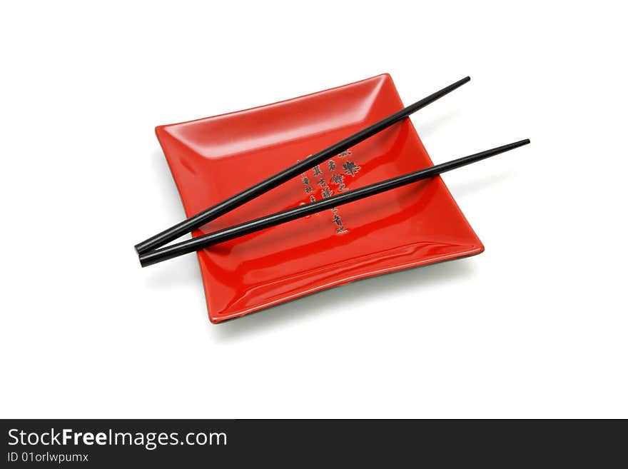 Chopsticks on  red square plate with kanji inscription isolated. Chopsticks on  red square plate with kanji inscription isolated