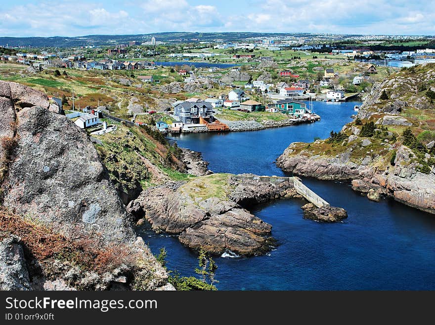 Aerial view of town on rocky coastline with inlet in foreground.