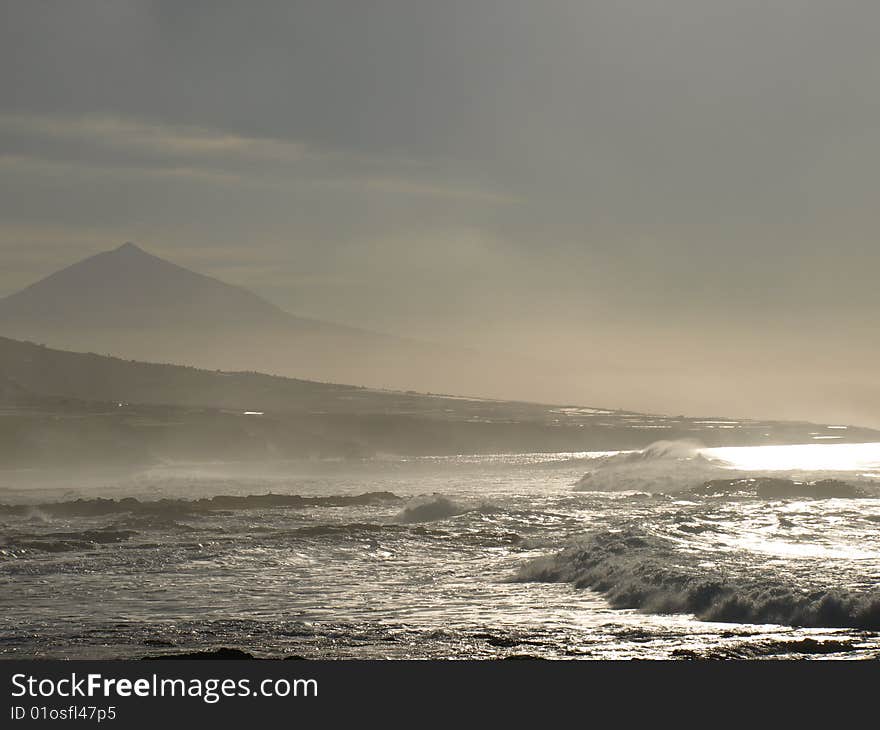 The setting sun turns the landscape and the Atlantic Ocean golden. The Mount Teide Volcano reaches into the sky in the background. The setting sun turns the landscape and the Atlantic Ocean golden. The Mount Teide Volcano reaches into the sky in the background.