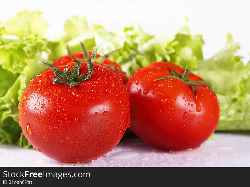 Two red fresh tomatoes and salad leaves