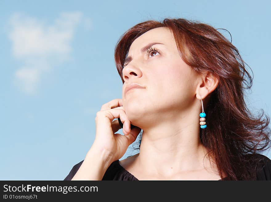 Woman talking by cellphone over sky background