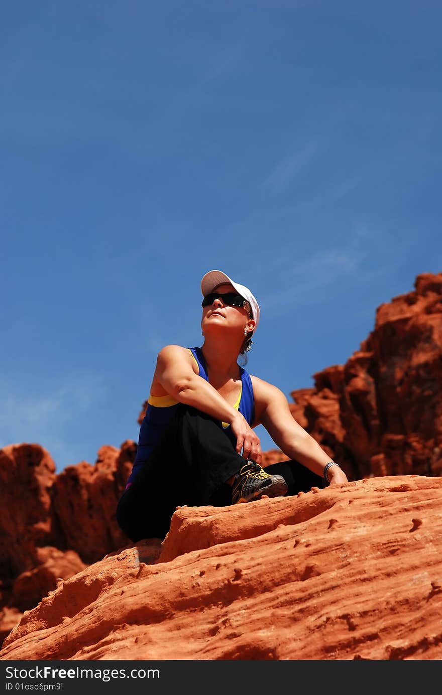 Enjoying Life, athletic woman sitting on rock hill in natural park