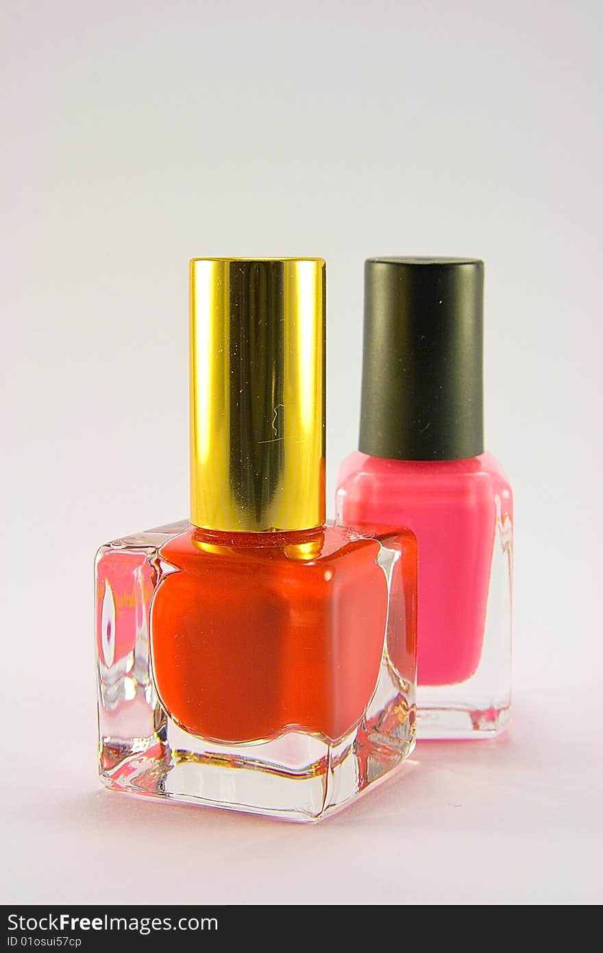 Bottles of red and pink nail polish on a plain background