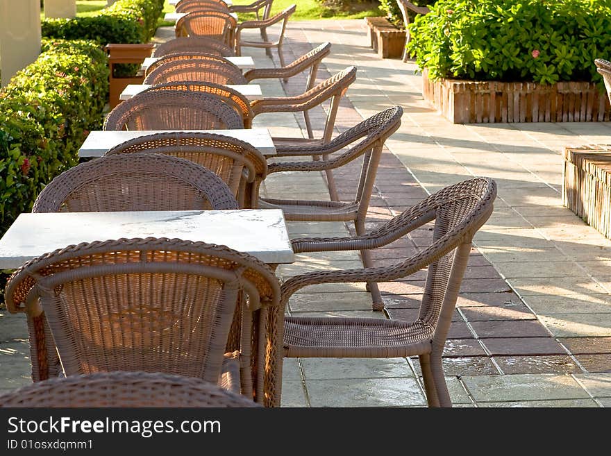 Table and four chairs on patio near bush and grass