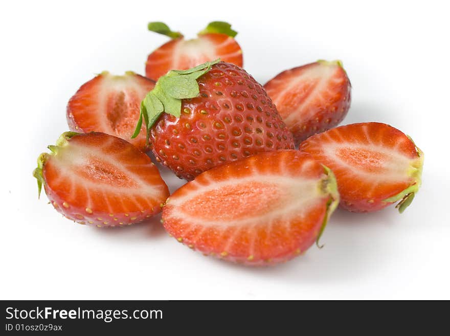 Whole strawberry and the berries of a strawberry cut on halves. A photo close up.