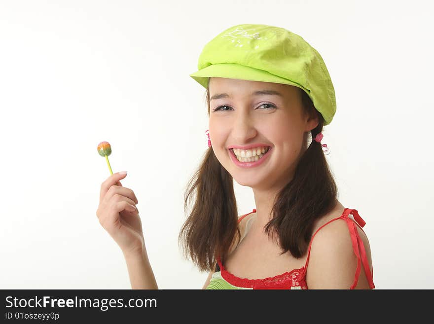 The girl in a green cap eats a sugar candy