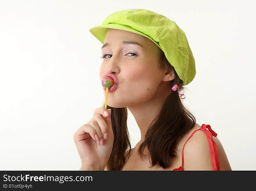 The girl in a green cap eats a sugar candy