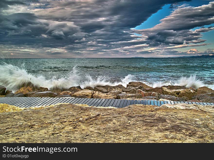 Waves hitting breakwater in cloudy day