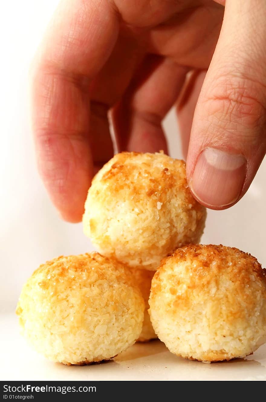 Clean coconut balls on a shiny plate with white background, one held by a hand. Clean coconut balls on a shiny plate with white background, one held by a hand