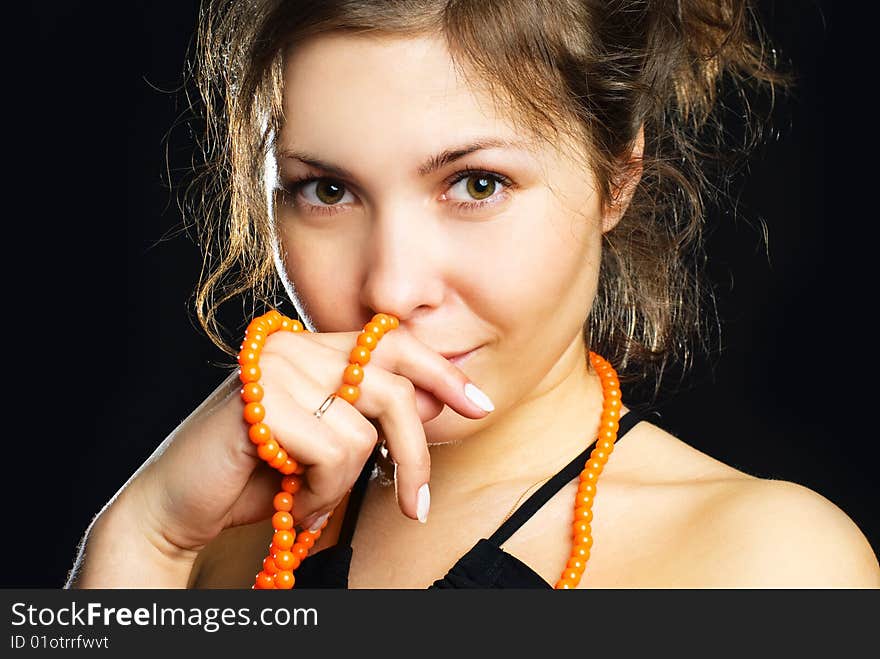 Studio portrait of a beautiful young brunette woman with orange beads. Studio portrait of a beautiful young brunette woman with orange beads