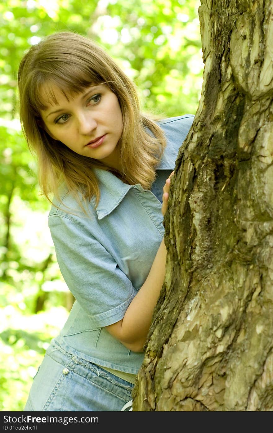 The beautiful girl in park to stand near an old tree. The beautiful girl in park to stand near an old tree