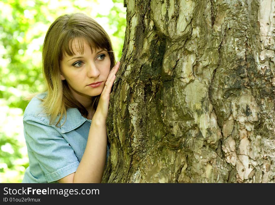 The beautiful girl in park to stand near an old tree. The beautiful girl in park to stand near an old tree