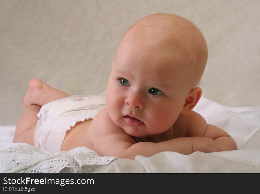 Serious 5 months old baby girl with diaper on white background