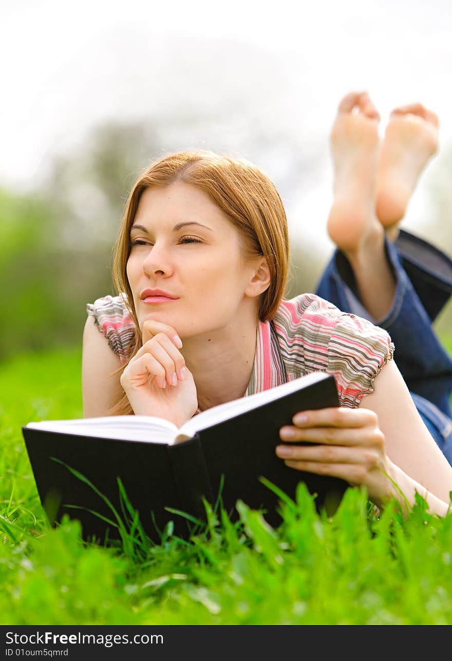 Pretty young woman reading outdoors. Pretty young woman reading outdoors