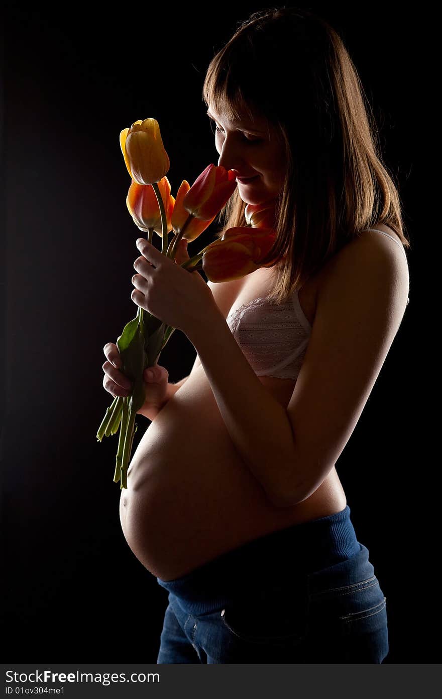 Beautiful bregnant woman with tulips over black. Beautiful bregnant woman with tulips over black