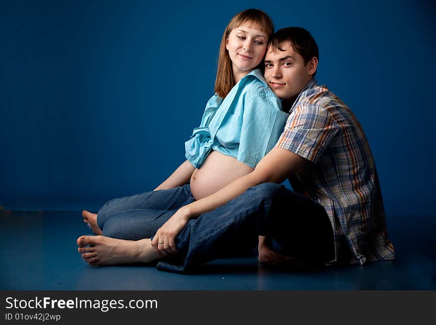 Beautiful couple waiting baby over blue