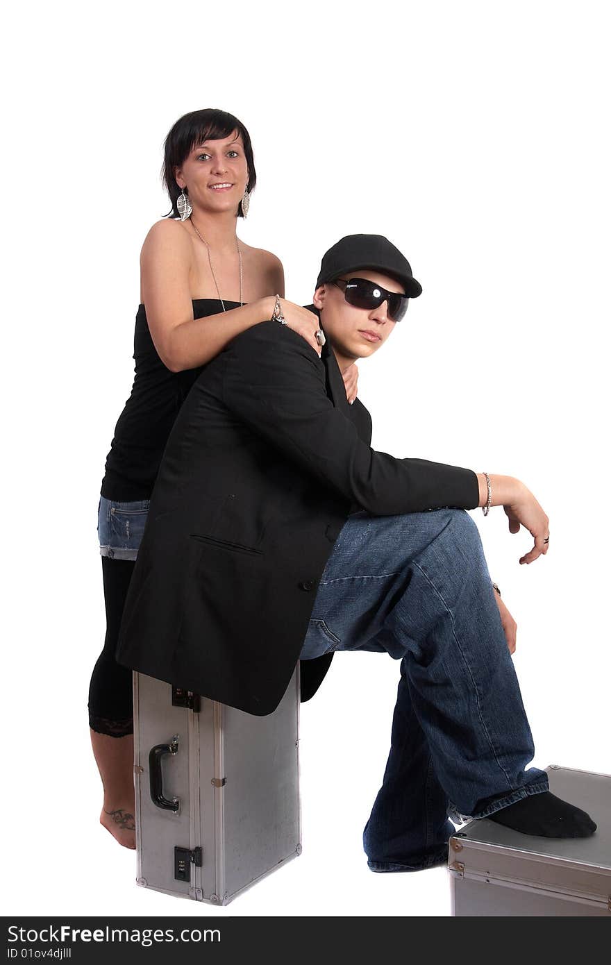 Young stylish couple isolated over white. He is sitting on dj cases. Young stylish couple isolated over white. He is sitting on dj cases.