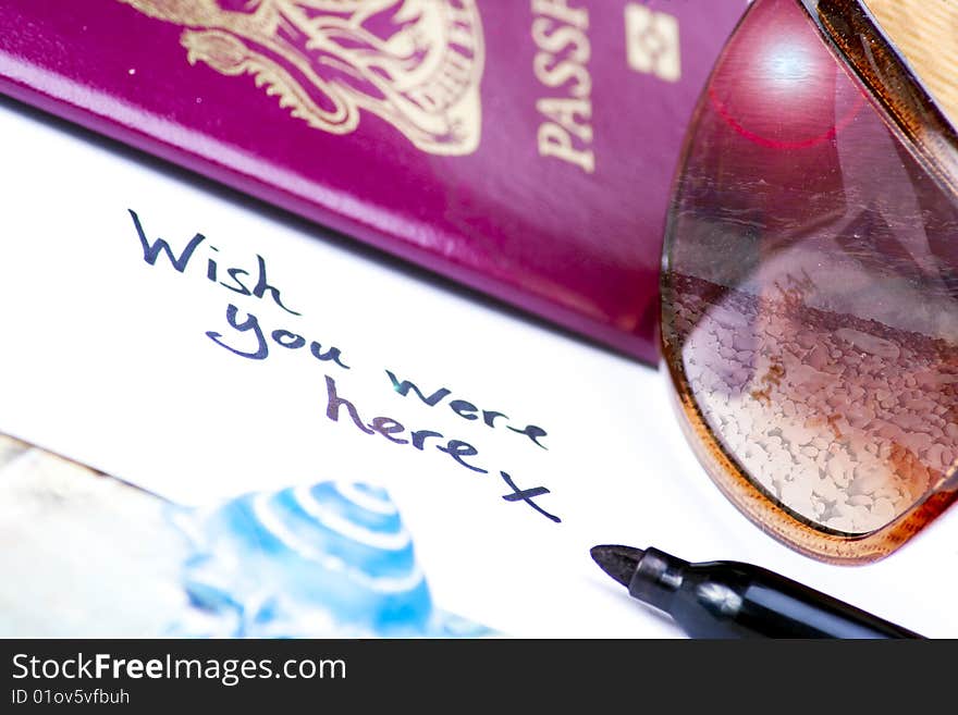 A postcard written with the phrase, wish you were here, with holiday essentials surround