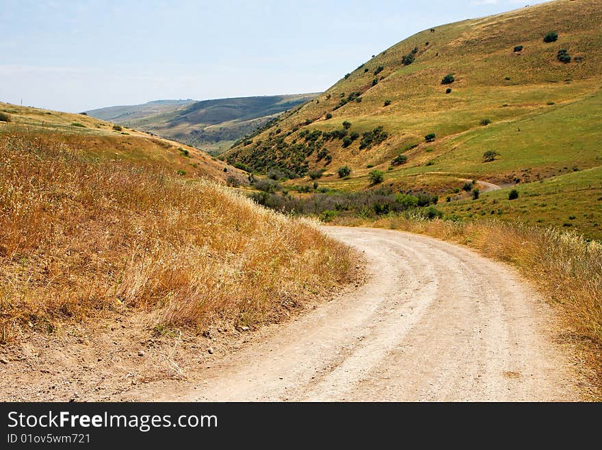 Countryside road bends among yellow hills