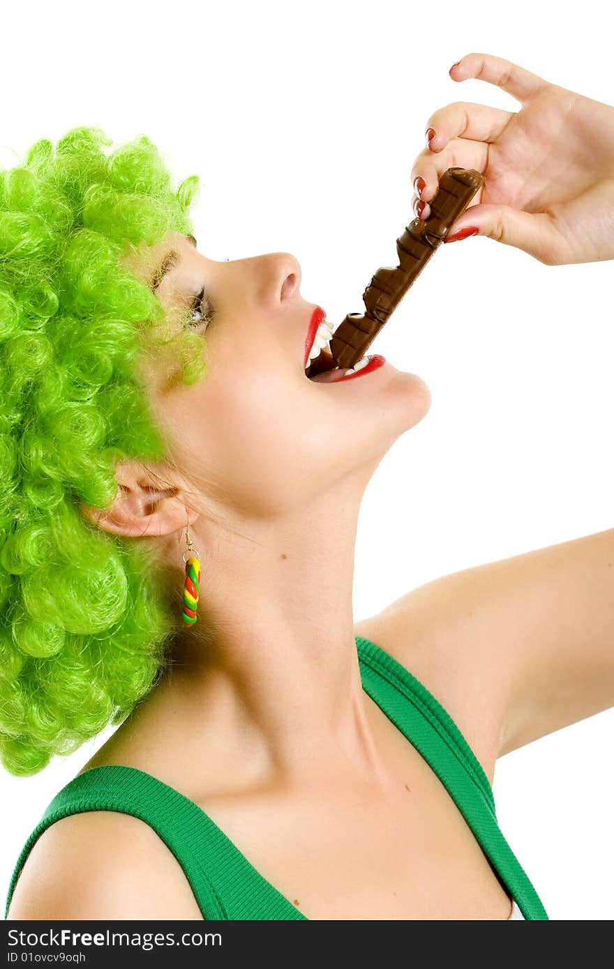 Closeup of an attractive woman with green wig biting a chocolate bar