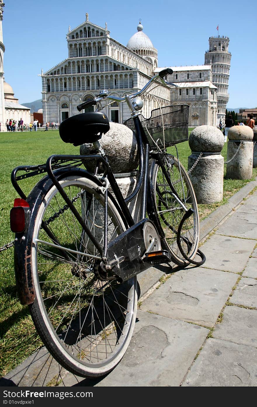 A bicycle in Pisa with a view of the leaning tower in the background