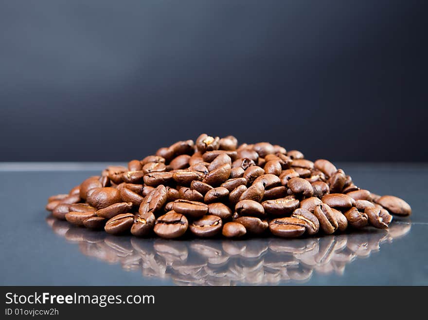 Heap of coffee beans on a glass surface