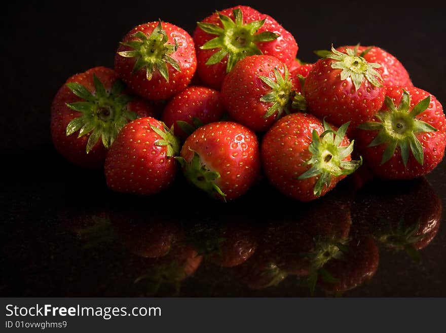 A pile of washed starwberries reflected in a granite work surface. A pile of washed starwberries reflected in a granite work surface