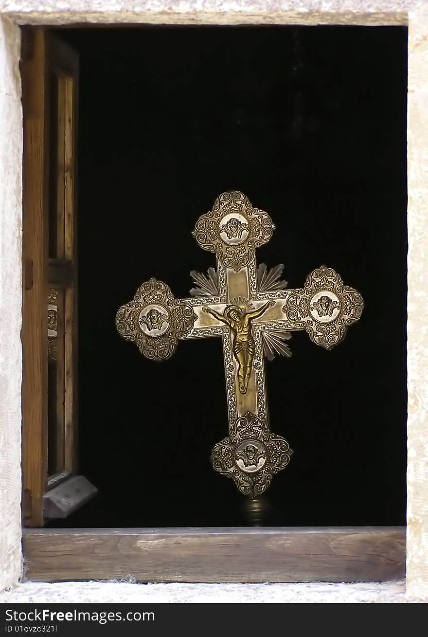 Golden cross in open window on old greek orthodox church against black background. Golden cross in open window on old greek orthodox church against black background.