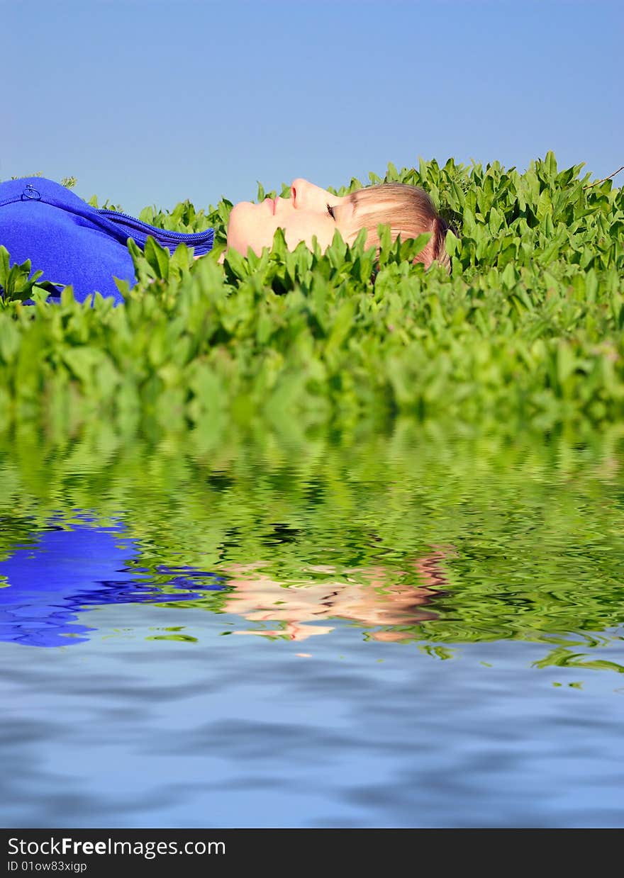 The girl sleeps in a grass near water