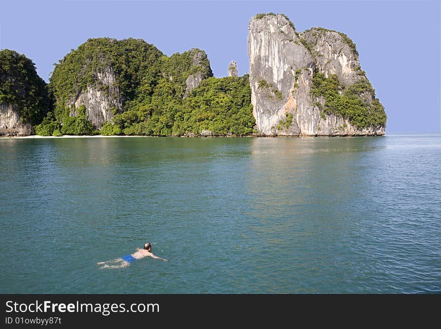 A man swimming in the ocean off a beautiful island