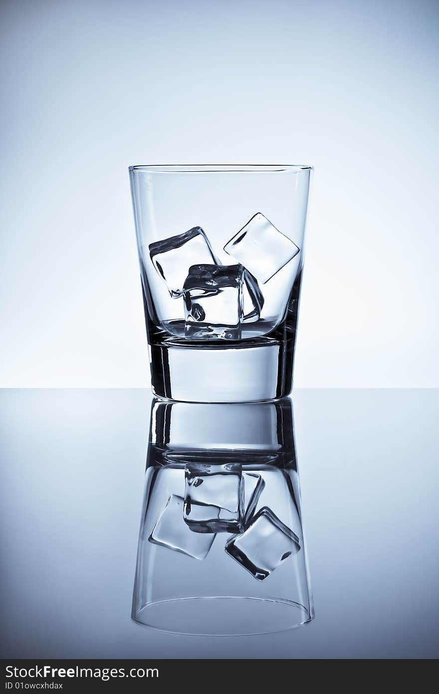 Tall tumbler filled with ice placed on a wet metallic tabletop. Tall tumbler filled with ice placed on a wet metallic tabletop.